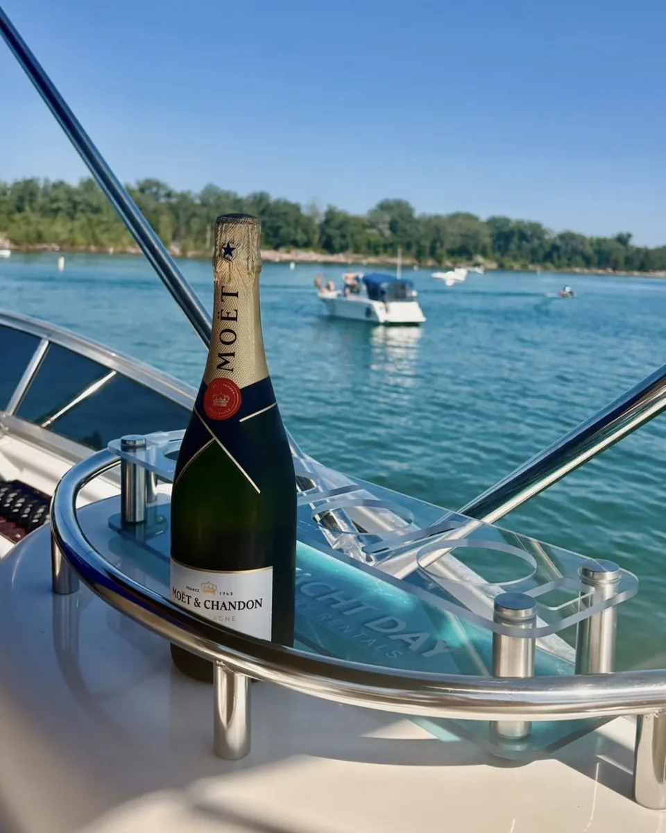 A bottle of champagne on the bow table, boats at anchor beyond.