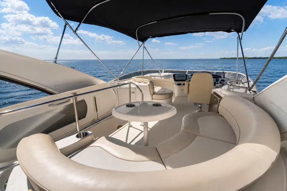 Upper deck seating and the helm under the bimini, open water beyond.